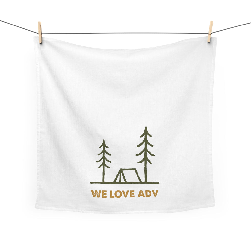 White towel with camping design and 'WE LOVE ADV' text hanging on a line.