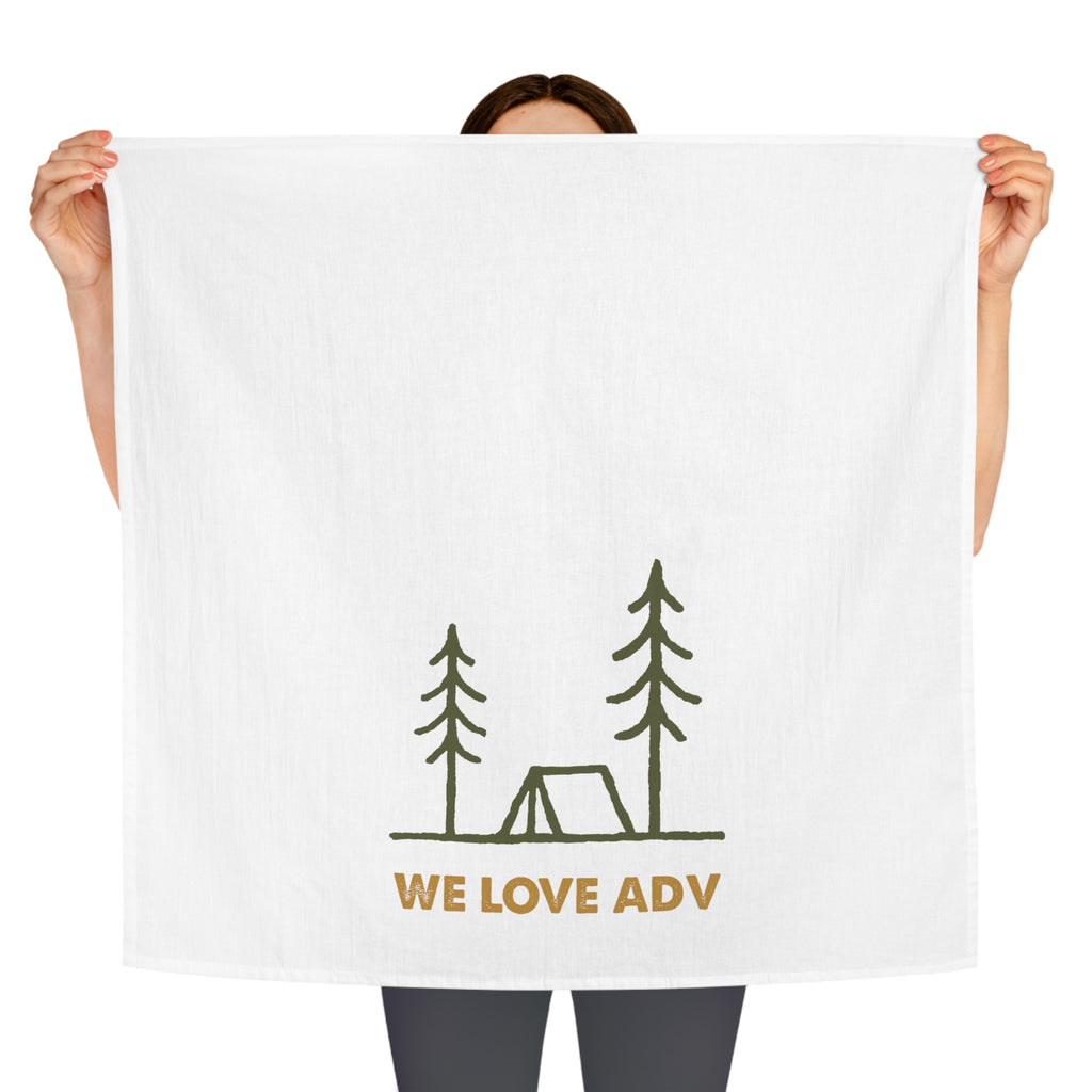 Person holding a white towel with 'WE LOVE ADV' and camping illustration on a white background