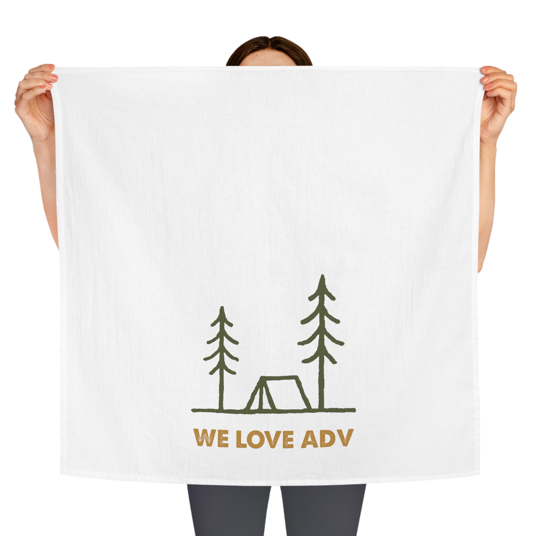 Person holding a white towel with 'WE LOVE ADV' and camping illustration on a white background