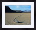 Desert landscape with a sliding rock and mountains in the background; framed photograph
